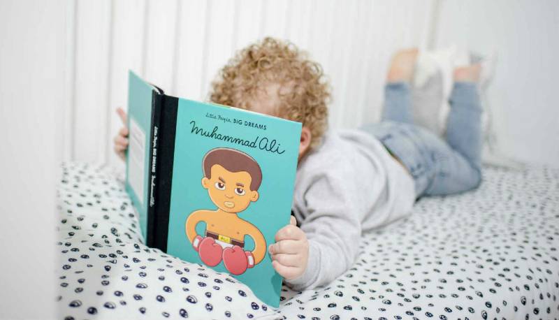 Little boy reading Little People Big Dreams Muhammad Ali