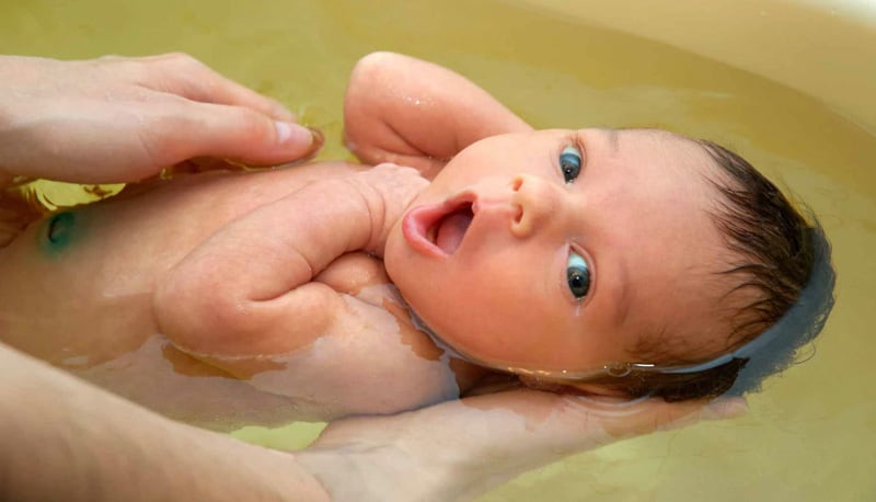 Baby being held up in bath 