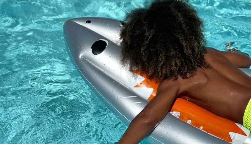 Boy lying on a Sunnylife float in a pool