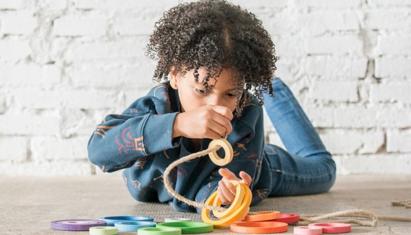 Child playing with coloured wooden rings